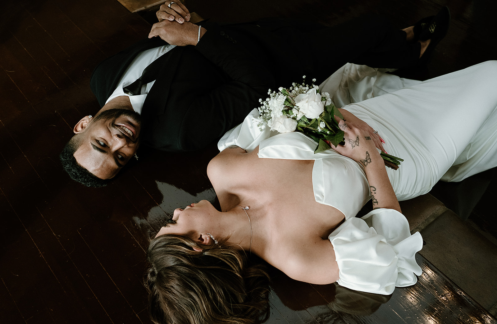 bride and groom lay together and gaze into each other's eyes